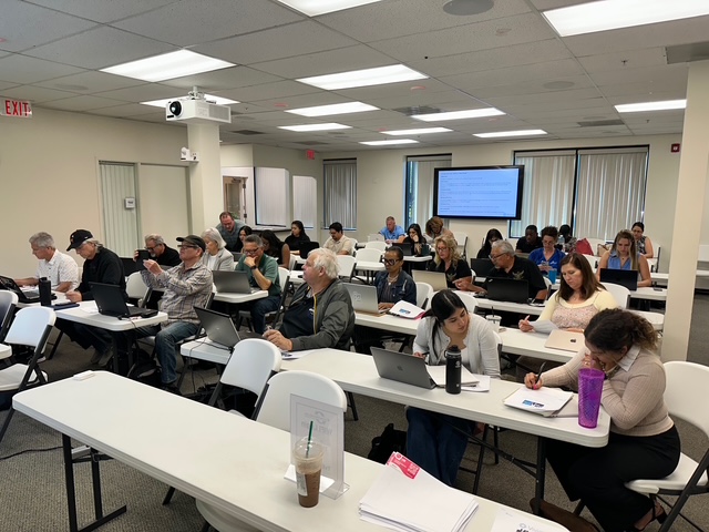 A room of professionals attending a Vivians.io AI training session, laptops open